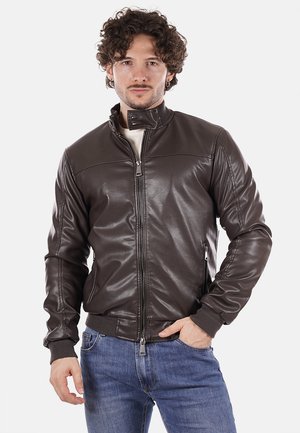 Giacca bomber in cuoio marrone con colletto alto, chiusura con zip frontale e polsini a costine. Tessuto liscio con dettagli di cucitura subtili sulle spalle.