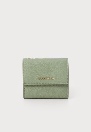 Green textured leather wallet with a fold-over closure and gold "Coccinelle" logo. Compact square shape with neat stitching details.