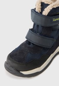 Granatowe buty sportowe z futrzanym wykończeniem, wykonane z zamszu i siateczki, z dwoma zapięciami na rzepy, teksturowaną podeszwą oraz wzmocnionym palcem zapewniającym trwałość.