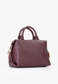 Borsa in pelle bordeaux con una forma strutturata, doppio manico e finiture in metallo color oro. Presenta una finitura testurizzata e una tasca laterale con zip.