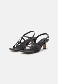 Schwarze Leder-Sandalen mit offenen Zehen, mehreren über Kreuz verlaufenden Riemen, einem niedrigen Blockabsatz und einem verstellbaren Schnallenknöchelriemen für einen sicheren Sitz.