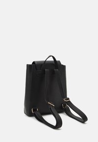 Mochila de cuero negro con un diseño estructurado, correas dobles para los hombros y un asa en la parte superior. Presenta detalles en hardware dorado.