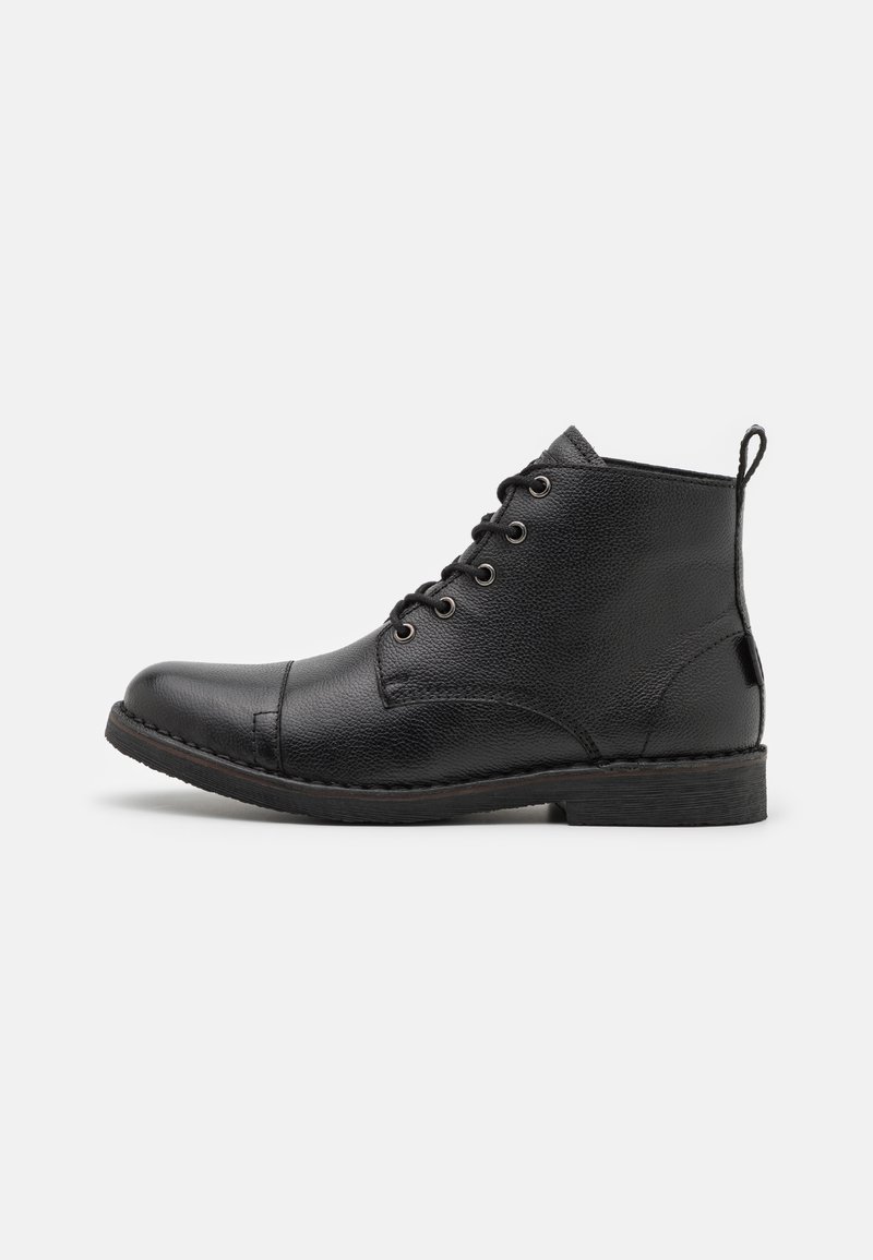 Bottines en cuir noir avec une surface texturée, bout rond, six œillets pour les lacets et une petite languette à l'arrière.