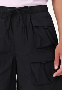 Black cargo shorts with a drawstring waistband, front and side pockets, and a soft, textured fabric. Features adjustable cord ends.