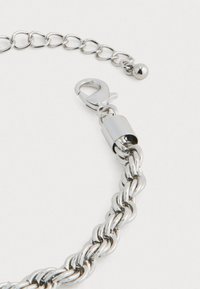 Ασημένια φουρφούρα αλυσίδα βραχιολιού με κούμπωμα αχιβάδας και ρυθμιζόμενη επέκταση που καταλήγει σε μια μικρή ασημένια χάντρα, πάνω σε λευκό φόντο.