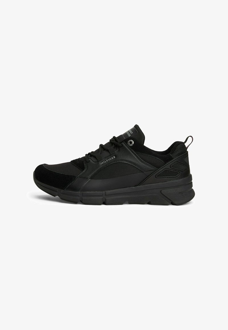 Black low-top sneaker with mixed materials, lace-up design, branded "Hilfiger" on side and tongue, and textured rubber sole.