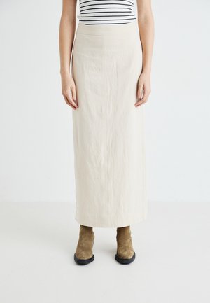 Beige Leinen-Maxi-Rock mit glatter Textur, hoher Taille und leichtem A-Linien-Schnitt, kombiniert mit braunen Wildleder-Stiefeletten.