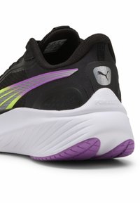 Musta juoksukenkä, jossa on teksturoitu päällinen ja liukuvärinen raita vihreänä ja purppuraisena. Valkoinen keskipohja, jossa purppuranvärisiä ulkopohjan yksityiskohtia.