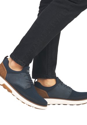 Sneakers blu navy con dettagli in rete e in tessuto marrone, suola in gomma bianca e lacci. Presentano un design elegante con punta arrotondata.