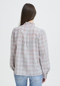 Karierte Bluse in den Farbtönen Blau, Pink und Beige. Leichter Stoff mit gerafftem Kragen und angesetzten Ärmeln. Rückenschlitz mit Kellerfalte.