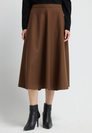 Bruine midi rok met een gestructureerd patroon, A-lijn ontwerp en een soepele tailleband, gecombineerd met zwarte enkellaarzen.