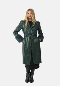 Ciemnozielony skórzany płaszcz trenchtowy z paskiem w talii i rękawami wykończonymi futrem, z kołnierzem z wycięciem i prostym krojem.