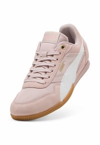 Zapatillas Puma con un upper de ante y textil rosa, acentos en blanco, cierre con cordones y una suela de goma con un patrón texturizado.