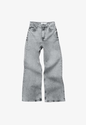 Jean en denim gris clair à jambes larges avec une taille haute, cinq poches et des coutures visibles. Le tissu a une finition texturée et une coupe droite.