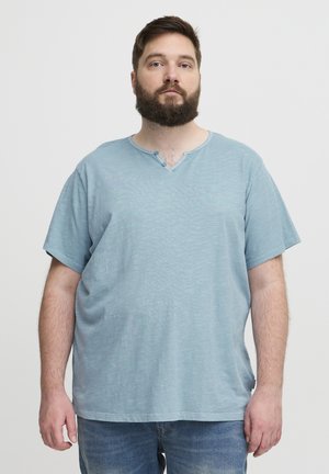 Camiseta de color azul claro, de manga corta y escote en V, hecha de una tela suave, con un pequeño detalle de botón en el escote. Ajuste casual y relajado.