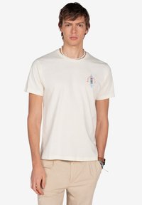 Camiseta de algodón color crema con mangas cortas, que presenta un gráfico estilizado de una tabla de surf en azul y rojo en la parte izquierda del pecho.