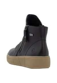 Bottines en cuir noir avec finition texturée, dotées d'une fermeture éclair sur le côté et d'une semelle en caoutchouc beige avec des rainures verticales.