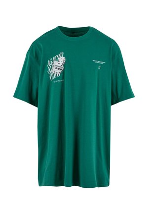 Zöld, laza szabású pamut póló, amelyen az elülső részen fehér színű dobókocka grafika és az "AGAINST ALL ODDS" felirat található.