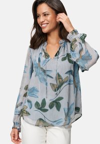 Floral-patterned blouse in light blue with green accents. Features a V-neck, gathered neckline, and elasticized cuffs. Lightweight fabric.
