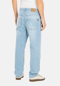 Vaqueros de mezclilla azul claro con corte recto, que cuentan con dos bolsillos traseros, un parche de cuero marrón claro con el logo en la cinturilla y detalles mínimos de costura.
