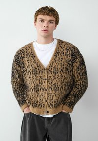 Leopardprint cardigan in bruin en zwart, gemaakt van zachte stof, met een v-hals, knoopsluiting en een losvallend ontwerp.