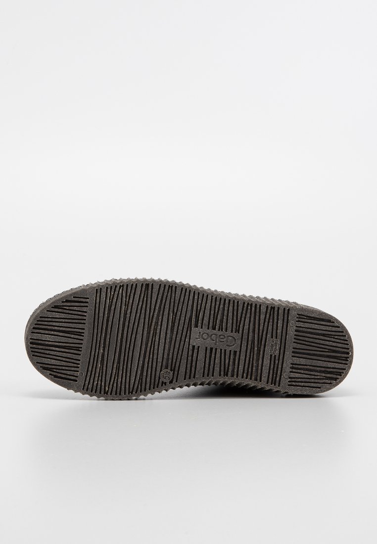 Semelle de chaussure en caoutchouc noir avec un motif texturé et strié et un logo en relief. Les formes circulaires des orteils et des talons améliorent la traction.