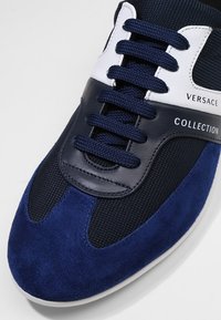 Marinblå sneakers med en blandning av mocka och mesh-material, vita detaljer, runda sn ören och en gummisula med varumärkesaccenter.