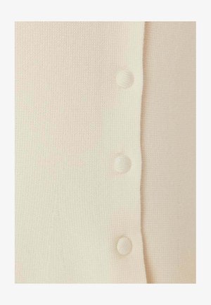 Nærbillede af cremegult stof med tre jævnt fordelt stofbetrukne knapper langs en lodret søm.