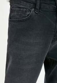 Jeans in denim nero con vestibilità regolare, design classico a cinque tasche e lavaggio delicato con texture sottile. Include una chiusura frontale con bottone e zip.
