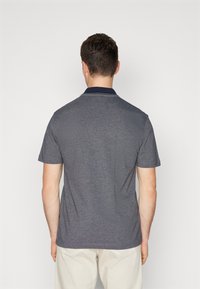 Pelēks īsām piedurknēm polo krekls ar tumši zilu apkakli un baltām akcentiem. Gluda tekstūra un brīvs piegriezums, ar klasisku dizainu.