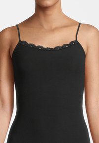 Top in cotone nero a costine con spalline sottili, caratterizzato da un bordo decorativo in pizzo lungo il collo per un tocco in più.