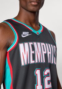 Tricou de baschet Nike negru cu "MEMPHIS" scris cu litere albe îndrăznețe. Accente turcoaz și roșu pe guler și pe laturi, cu numărul 12.