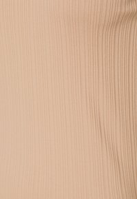 Tessuto a coste, morbido, di un colore beige chiaro, con sottili linee verticali e una superficie liscia. Nessun hardware o accento visibile.