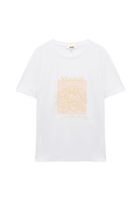Camiseta blanca de algodón con un diseño de flor de loto en color durazno y texto que dice "La mentalidad lo es todo" en un estilo minimalista.
