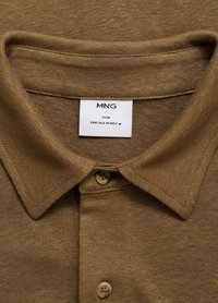 Polo shirt slim-fit marrone realizzato in tessuto testurizzato, con colletto a bottoni e un'etichetta con informazioni su marca e taglia.