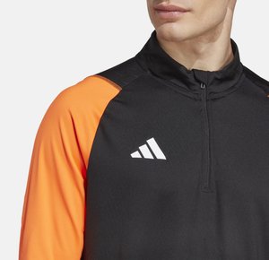 Zwarte sportieve pullover met oranje mouwen, halve rits en een wit Adidas-logo op de borst. Gemaakt van soepele, lichte stof.