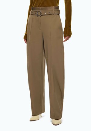 Pantalones anchos marrones de talle alto con cinturón a juego, combinados con un top de manga larga mostaza acanalado y tacones beige puntiagudos.