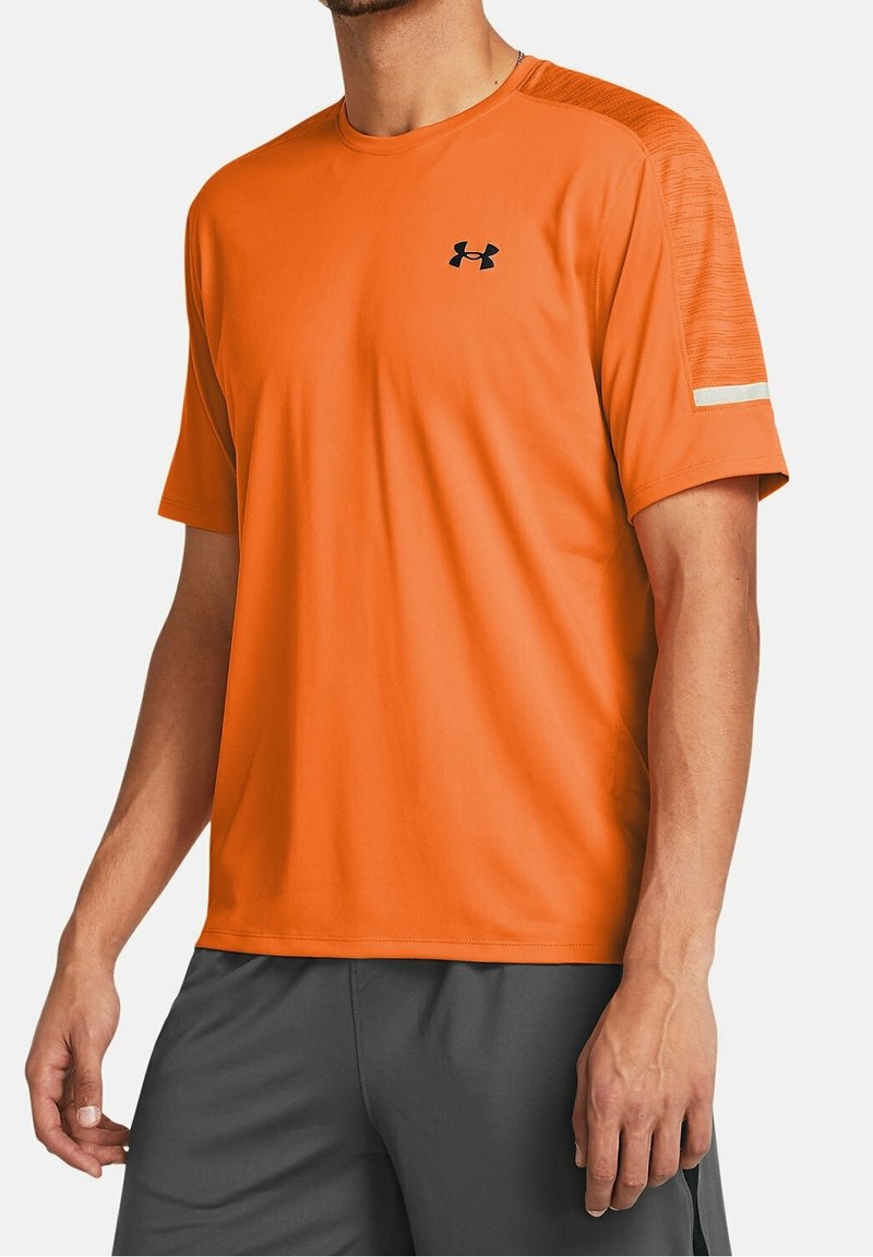 Orange atletisk t-shirt av lätt material, med rund hals, korta ärmar och texturerade axelinslag. Svart logotyp på bröstet.