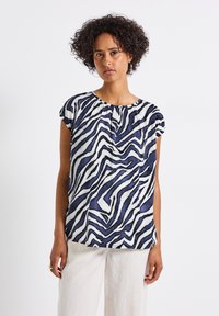 Blusa a strisce zebra blu navy e bianca con maniche corte, tessuto fluido e scollatura arrotondata, caratterizzata da pieghe davanti e una vestibilità comoda.