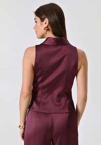 Top sans maniche in satin bordeaux con colletto, vestibilità aderente e texture liscia, visto da dietro.