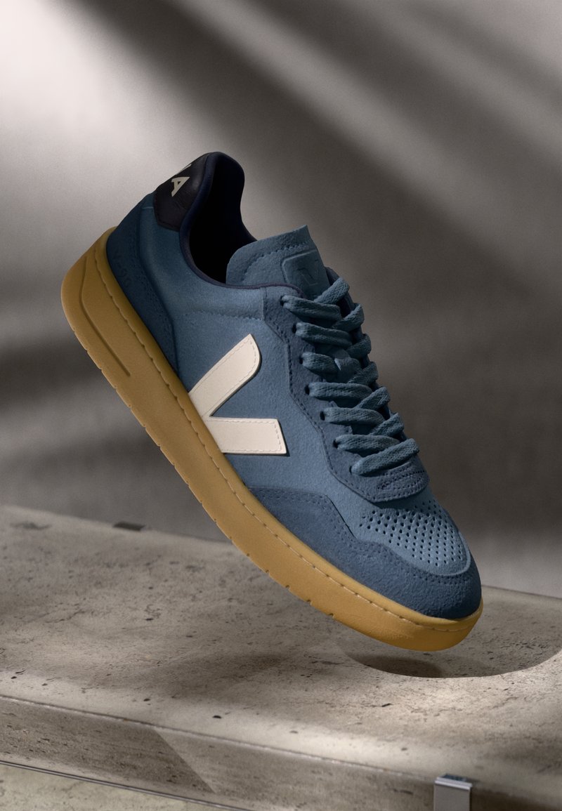 Le sneaker blu in pelle scamosciata hanno un dettaglio del logo bianco, una zona delle dita perforata e una suola in gomma. Il design include un collo imbottito.