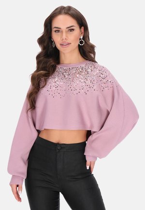 Roze cropped trui met geribbelde textuur, versierd met (gouden) pailletten op de halslijn, gecombineerd met zwarte slim-fit broeken.