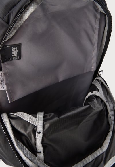 Ανοιχτό μαύρο και γκρι σακίδιο πλάτης που δείχνει το άδειο κύριο διαμέρισμα με υφασμάτινη ετικέτα στην εσωτερική πτέρυγα.