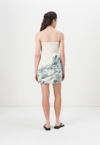 Mouwloze jurk van licht materiaal met een groene tropische print. Smalle textuur, snit boven de knie, met verstelbare banden en een aangesloten lijfje.