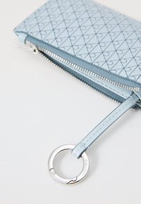 Portafoglio zippato azzurro chiaro con motivo a diamante, cerniera argentata e un anello circolare fissato con un cinturino coordinato.