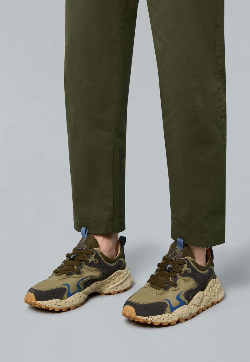 Olivově zelené a černé tenisky s texturovanou podešví, modrými akcenty a kombinací materiálů. Unikátní design s tečkovanými detaily.