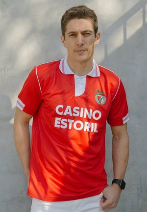 Rode voetbalshirt met witte accenten, voorzien van een kraag en korte mouwen. Op de voorkant staat "CASINO ESTORIL" in vette letters.