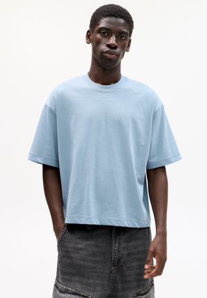 Lyseblå bomulds t-shirt med afslappet pasform, korte ærmer og rund hals. Båret med mørkegrå, løstsiddende denim shorts.