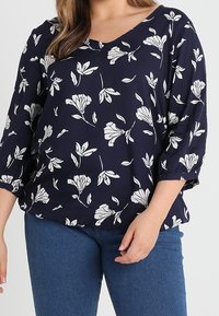 Laivastonsininen kukkakuosiselkäpaita, jossa on V-pääntie, kolmannelta kvartaali hihoilla ja valkoisia kukkakuoseja; pehmeä kangas ja löysä malli.