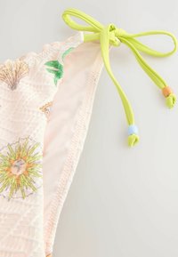 Roza bikini zgornji del z vzorci morskih školjk in sonca, z teksturirano površino in zelenimi zavezanimi trakovi ter obarvanimi perlicami.